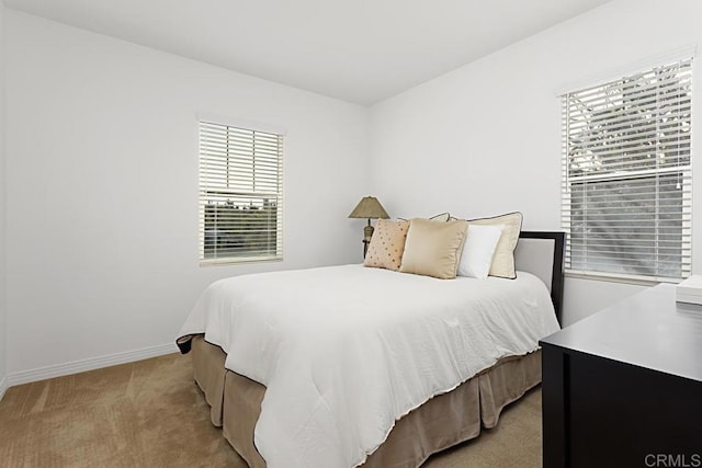 bedroom featuring light carpet and baseboards