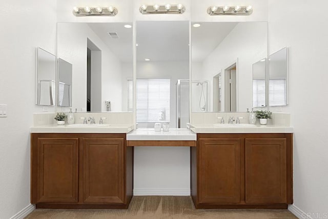 full bath featuring a sink, two vanities, and a stall shower