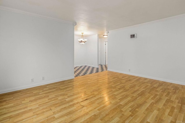 empty room with visible vents, baseboards, light wood-style flooring, ornamental molding, and a notable chandelier