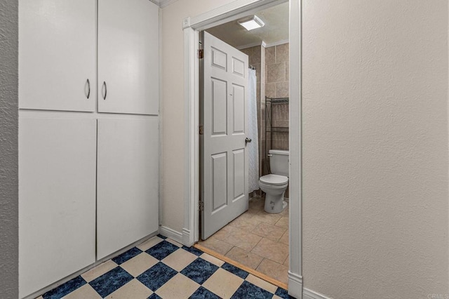 full bathroom with a shower with shower curtain, toilet, tile patterned floors, and a textured wall