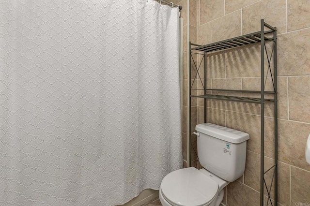 bathroom with a shower with shower curtain, toilet, and tile walls