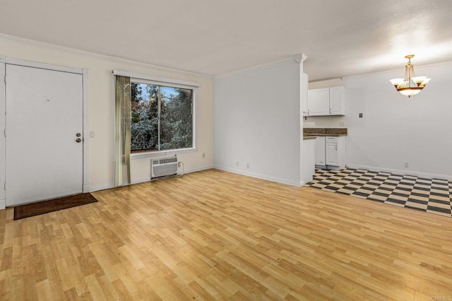 unfurnished living room featuring a wall mounted air conditioner, light wood-style floors, crown molding, baseboards, and a chandelier