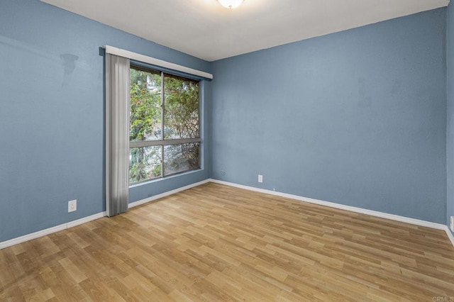 empty room with wood finished floors, baseboards, and a healthy amount of sunlight