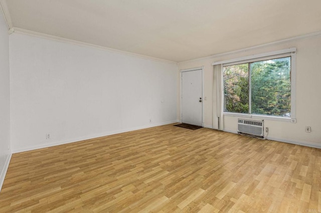 unfurnished room featuring light wood-style flooring, a wall mounted air conditioner, crown molding, and baseboards