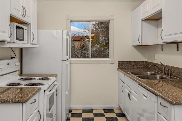 kitchen with white appliances, light floors, baseboards, a sink, and white cabinets