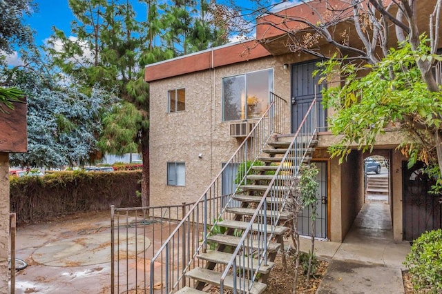 exterior space with stairs, cooling unit, and stucco siding