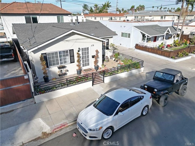 view of front of house with a residential view, a fenced front yard, and stucco siding