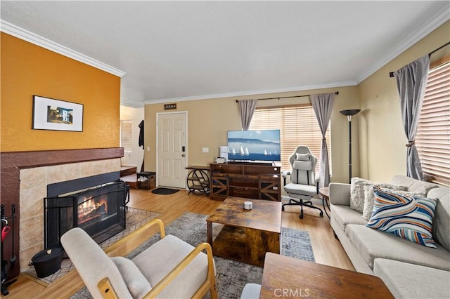 living room with a tiled fireplace, crown molding, and wood finished floors