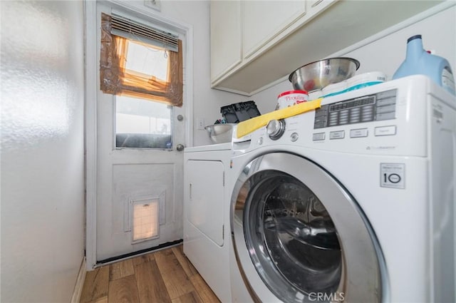 laundry area featuring washing machine and dryer, cabinet space, and wood finished floors