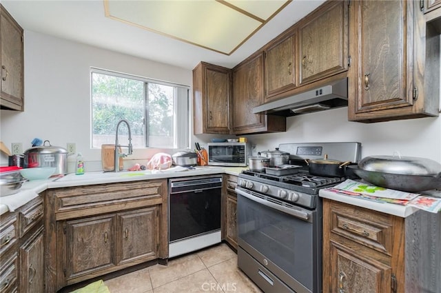 kitchen featuring light tile patterned floors, a sink, light countertops, appliances with stainless steel finishes, and under cabinet range hood