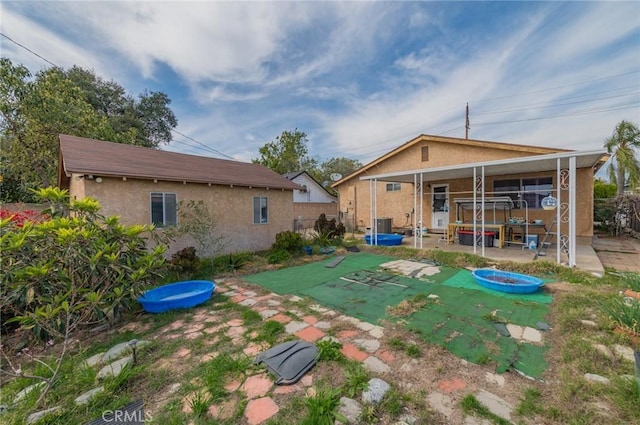 back of property with stucco siding, a patio, and fence