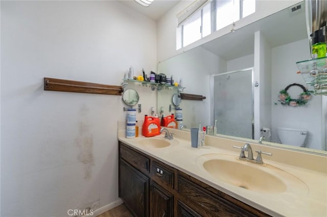 bathroom with a sink, toilet, double vanity, and a shower stall