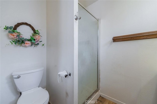 full bath with wood finished floors, toilet, and a stall shower