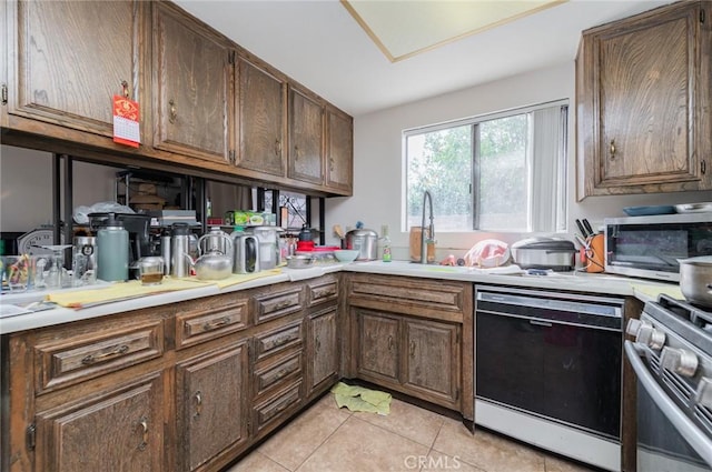 kitchen with light tile patterned floors, appliances with stainless steel finishes, light countertops, and a sink