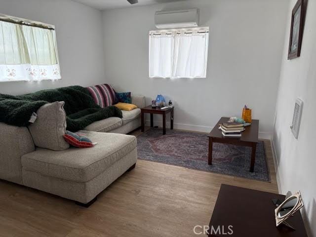 living area featuring a wealth of natural light, a wall unit AC, and wood finished floors