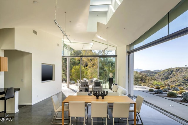 dining area featuring visible vents, baseboards, floor to ceiling windows, a mountain view, and high vaulted ceiling