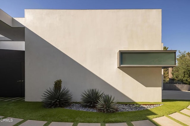 view of side of property featuring stucco siding and a lawn