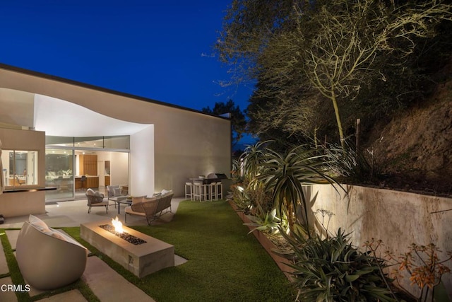 yard at night featuring an outdoor fire pit and a patio