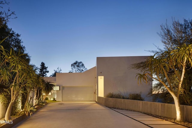 view of front of home featuring stucco siding, concrete driveway, and a garage