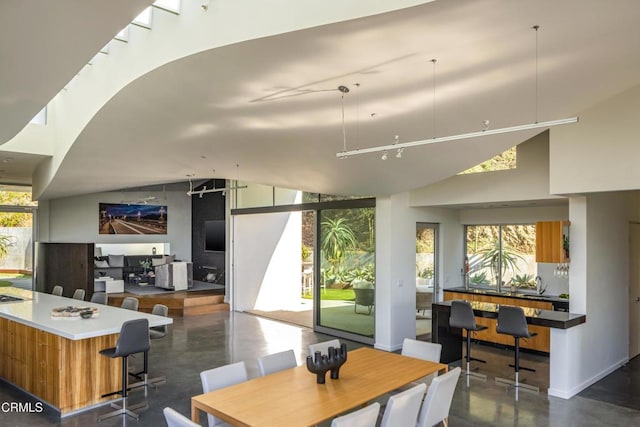 dining space featuring plenty of natural light, finished concrete flooring, and high vaulted ceiling