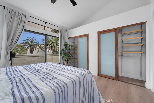 bedroom featuring a ceiling fan, wood finished floors, baseboards, vaulted ceiling, and multiple closets