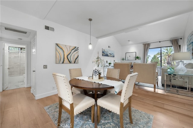 dining area with visible vents, lofted ceiling, and light wood-style flooring