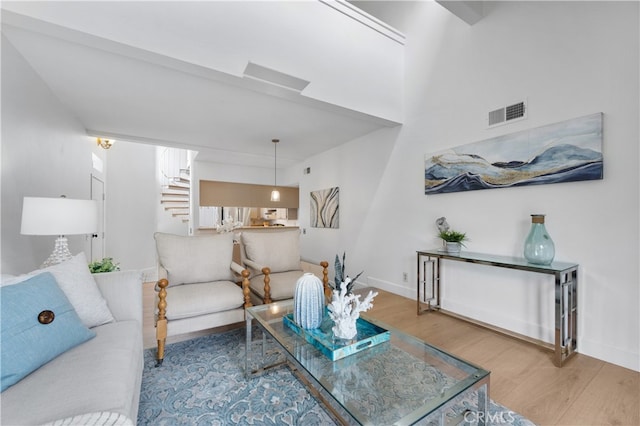 living room with visible vents, baseboards, wood finished floors, and stairs