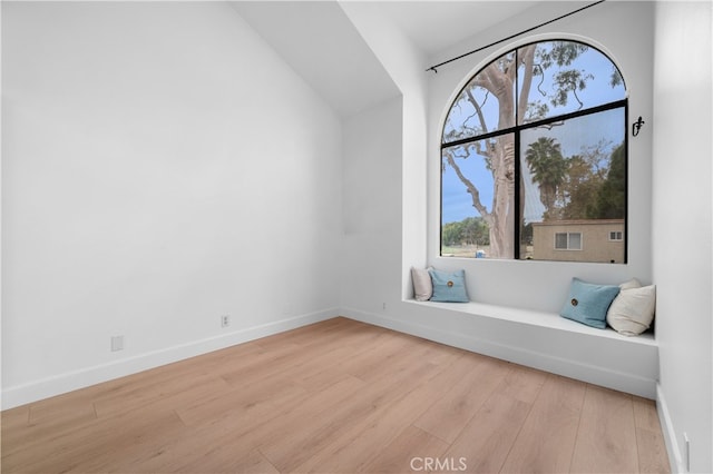 unfurnished room with baseboards, wood finished floors, and vaulted ceiling