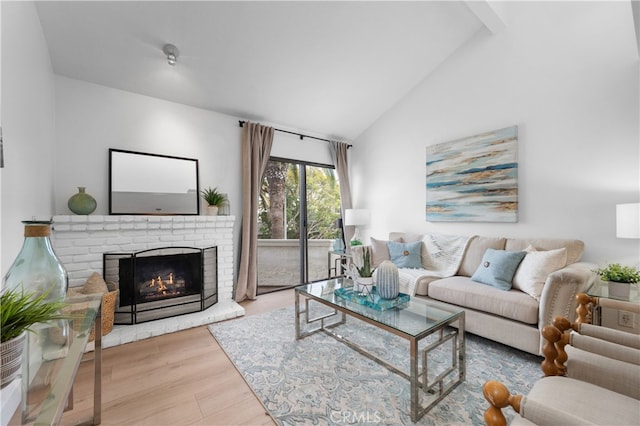 living area with a brick fireplace, high vaulted ceiling, and wood finished floors