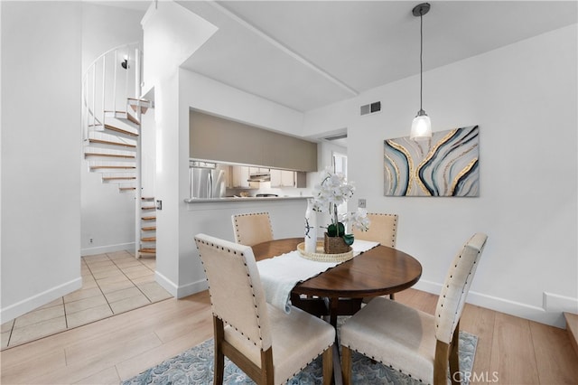 dining room featuring stairs, light wood-style flooring, baseboards, and visible vents