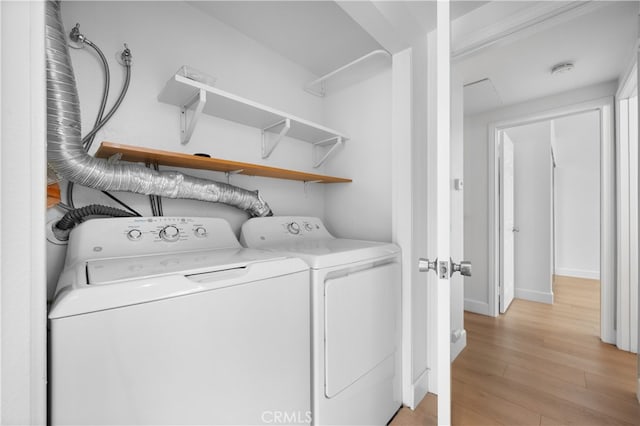 clothes washing area with light wood-style flooring, washing machine and dryer, and laundry area