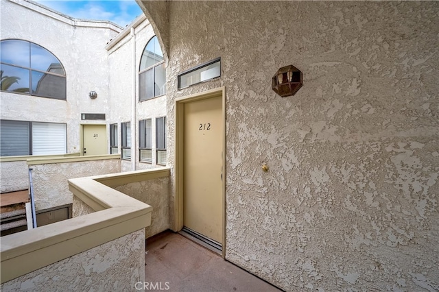 entrance to property featuring stucco siding and a balcony