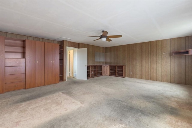 interior space with wooden walls, ceiling fan, and carpet