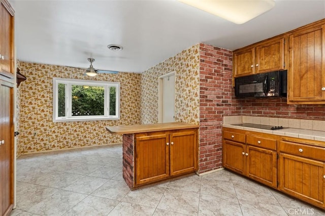 kitchen with visible vents, brown cabinets, and black appliances