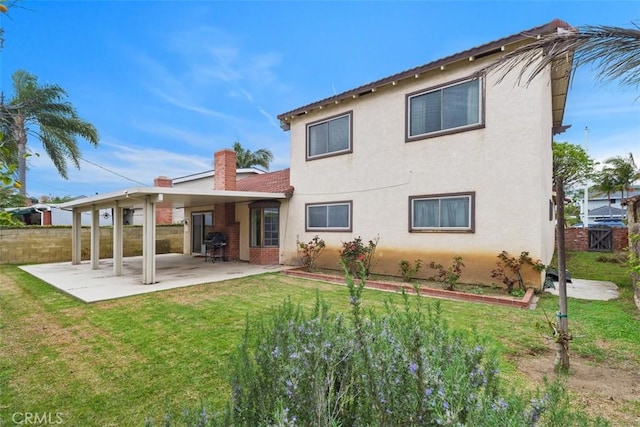 back of house featuring a patio area, a lawn, fence, and stucco siding