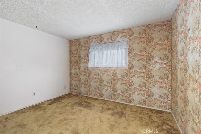 carpeted empty room with a textured ceiling