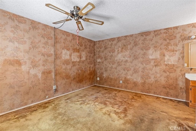 unfurnished room with wallpapered walls, a textured ceiling, a ceiling fan, and carpet