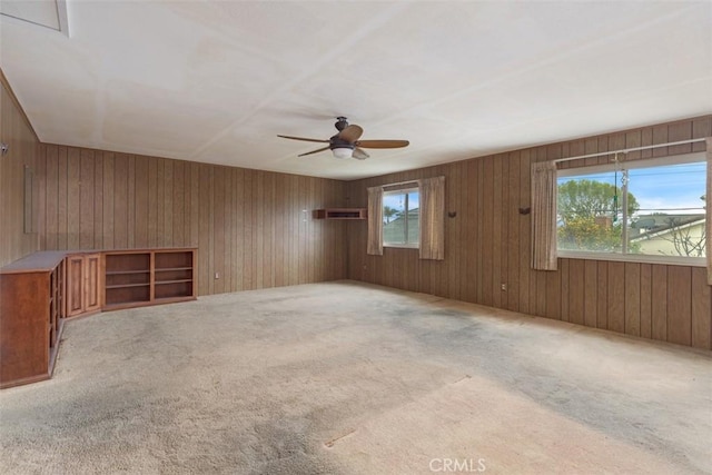 interior space with a ceiling fan, wooden walls, and carpet flooring