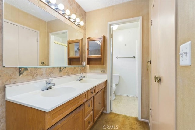 bathroom featuring double vanity, toilet, and a sink