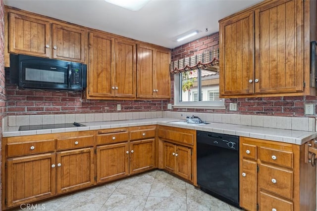 kitchen featuring brown cabinetry, light tile patterned flooring, black appliances, and a sink