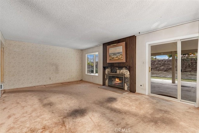 unfurnished living room featuring a stone fireplace, carpet floors, and a textured ceiling