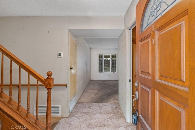 foyer entrance with visible vents, a textured ceiling, and stairway