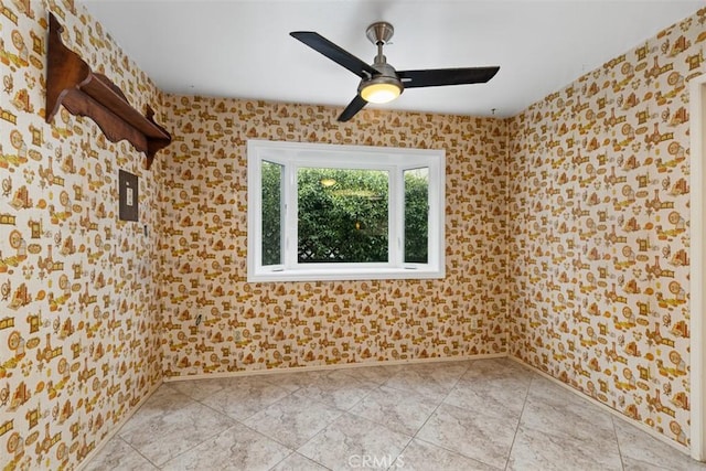 empty room featuring a ceiling fan and baseboards