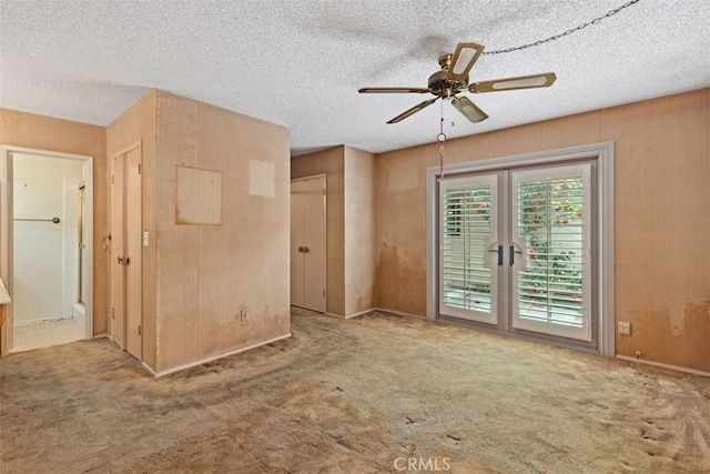 carpeted spare room with french doors, a textured ceiling, and a ceiling fan