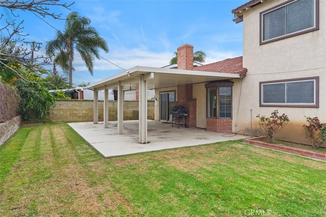 back of property featuring a yard, fence, a chimney, and a patio area