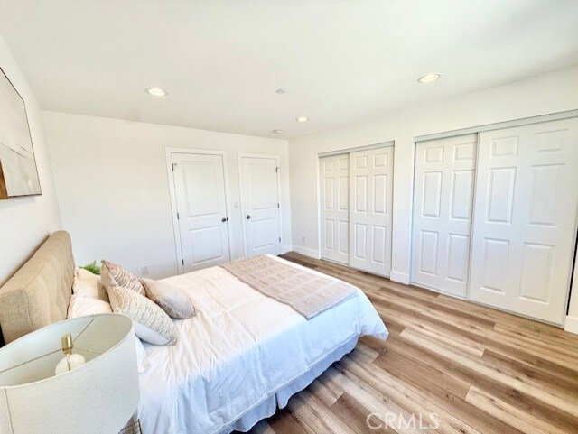 bedroom with baseboards, two closets, recessed lighting, and light wood-style flooring