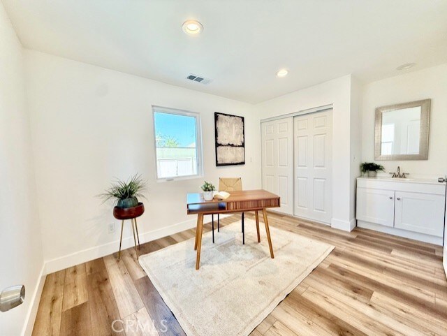 home office featuring visible vents, baseboards, recessed lighting, a sink, and light wood finished floors
