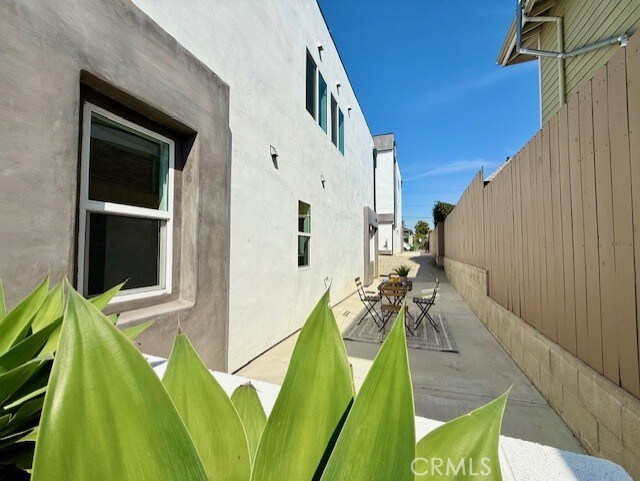 view of side of property featuring fence, a patio, and stucco siding