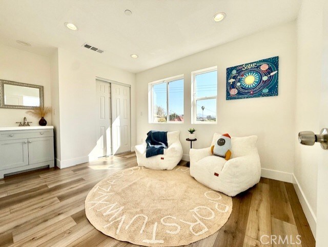 living area with recessed lighting, baseboards, visible vents, and wood finished floors