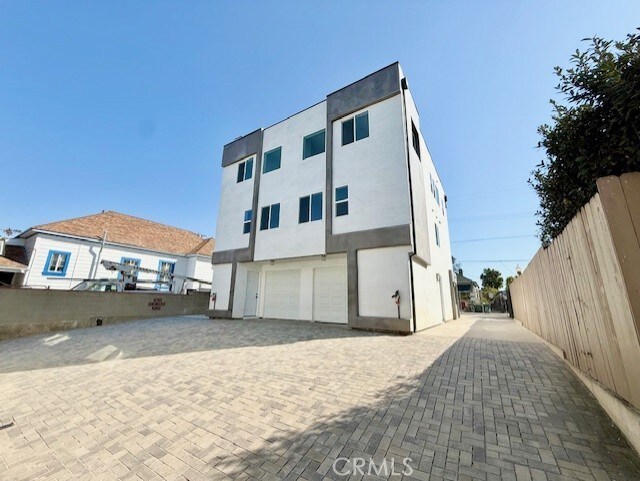 back of house featuring stucco siding, a garage, and fence